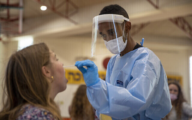 Un travailleur médical teste un jeune Israélien pour le coronavirus sur un terrain de basket transformé en centre de dépistage du coronavirus à Binyamina, en Israël, mardi 29 juin 2021. (Crédit : APPhoto/Ariel Schalit)