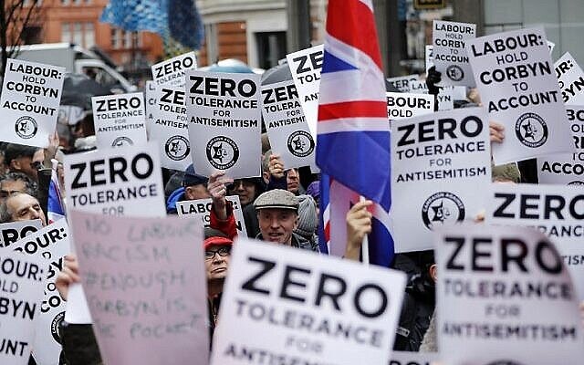 Illustration : Des personnes brandissent des pancartes et des drapeaux de l'Union alors qu'elles se rassemblent pour une manifestation organisée par la Campagne contre l'antisémitisme devant le siège du Parti travailliste, l'opposition britannique, dans le centre de Londres, le 8 avril 2018. (Crédit : AFP/Tolga Akmen)