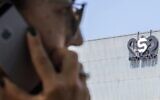 Sur cette photo d'archive prise le 28 août 2016, une Israélienne utilise son iPhone devant le bâtiment abritant le groupe israélien NSO, à Herzliya, près de Tel Aviv. (Crédit : Jack Guez/AFP)