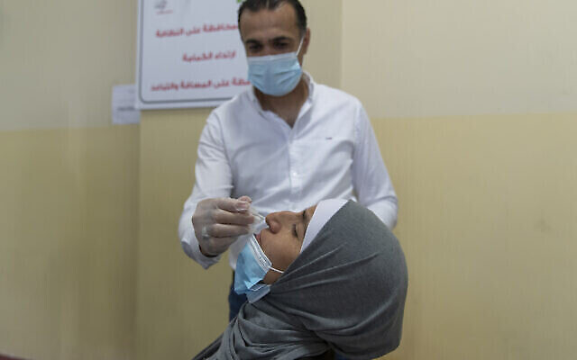 Un agent de santé prélève un échantillon nasal sur une femme palestinienne dans un centre de dépistage du COVID-19, dans la ville de Ramallah, en Cisjordanie, le dimanche 6 juin 2021. (Crédit: AP Photo/Nasser Nasser)