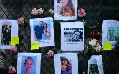 Des photos d'Andres Levine, Ilan Naibryf et Deborah Berezdivin, trois des victimes juives de l'effondrement de l'immeuble de Surfside, au centre parmi d'autres photos des disparus affichées sur un mémorial de fortune sur le site de l'immeuble à Surfside, en Floride, le 26 juin 2021. (Crédit : Andrea Sarcos/AFP)