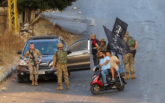Des partisans du Hezbollah portent des drapeaux sur des motos devant des soldats libanais alors que l'armée se déploie au milieu d'affrontements dans la région de Khalde, au sud de la capitale, le 1er août 2021 (Crédit : ANWAR AMRO / AFP).