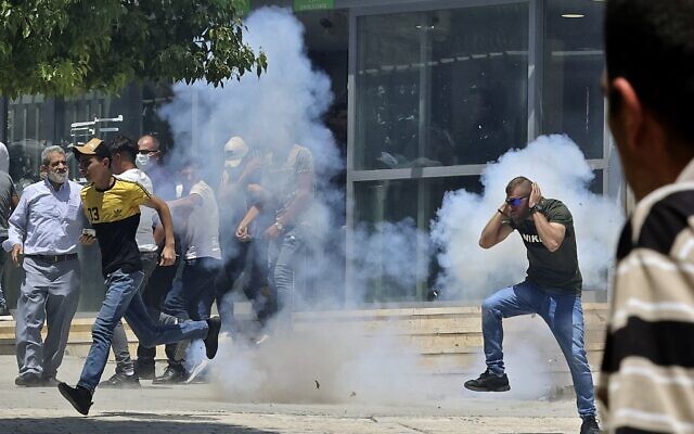 Des manifestants palestiniens courent pour éviter les gaz lacrymogènes pendant des affrontements avec les forces israéliennes de sécurité lors d'une manifestation qui a eu lieu après la prière du vendredi à la mosquée Ibrahimi (Tombeau des patriarches), le 13 août 2021. (Crédit : HAZEM BADER / AFP)