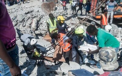 Des Haïtiens recherchent des survivants parmi les décombres dans le quartier de Dexia 6, aux Cayes, à Haïti, le 15 août 2021, après qu'un séisme de magnitude 7,2 a frappé la péninsule sud-ouest du pays. (Crédit : Réginald LOUISSAINT JR / AFP)