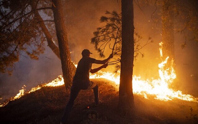 Un Marocain tente d'éteindre un incendie alors que des incendies sauvages ont détruit quelque 200 hectares de forêt dans la région de Chefchaouen, dans le nord du Maroc, le 15 août 2021. (Crédit : FADEL SENNA / AFP)