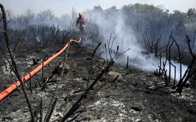 Les pompiers français utilisent un tuyau d'arrosage pour éteindre un incendie à Gonfaron, dans le département français du Var, dans le sud de la France, le 17 août 2021. (Photo par NICOLAS TUCAT / AFP)