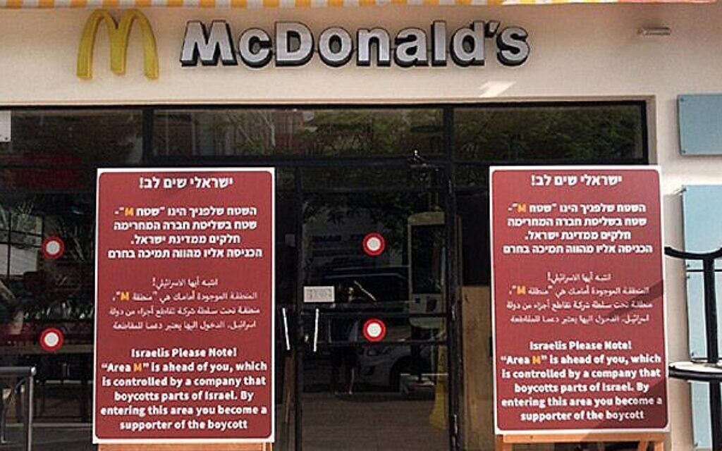 Des panneaux placés devant des succursales de McDonald's accusant la chaîne de restauration rapide de boycotter les implantations de Cisjordanie, et exhortant les Israéliens à boycotter le géant de la restauration en retour, à Tel Aviv, le 4 juin 2019. (Crédit : Capture d'écran de la Douzième chaîne) Des panneaux placés devant des succursales de McDonald's accusant la chaîne de restauration rapide de boycotter les implantations de Cisjordanie, et exhortant les Israéliens à boycotter le géant de la restauration en retour, à Tel Aviv, le 4 juin 2019. (Crédit : Capture d'écran de la Douzième chaîne)