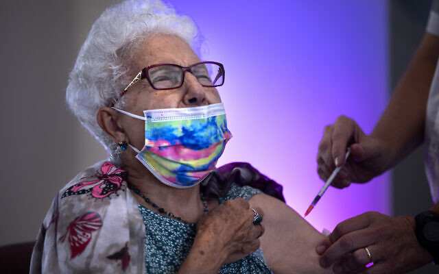 Rachel Gershon, 83 ans, reçoit une troisième dose de vaccin Pfizer-BioNTech administrée par un bénévole du Magen David Adom dans une maison de retraite de Netanya, le 1er août 2021. (Crédit : AP Photo/Oded Balilty)