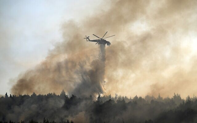 Un hélicoptère largue de l'eau sur un incendie dans la zone de Varibobi, au nord d'Athènes, en Grèce, le 4 août 2021. (Crédit : AP Photo/Thanassis Stavrakis)