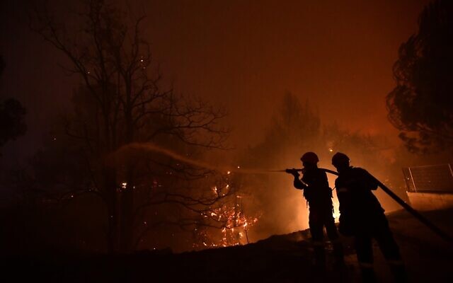 Des pompiers tentent d'éteindre un feu de forêt dans la région d'Afidnes, au nord d'Athènes, en Grèce, le jeudi 5 août 2021. (Crédit : AP/Michael Varaklas) Des pompiers tentent d'éteindre un feu de forêt dans la région d'Afidnes, au nord d'Athènes, en Grèce, le jeudi 5 août 2021. (Crédit : AP/Michael Varaklas)