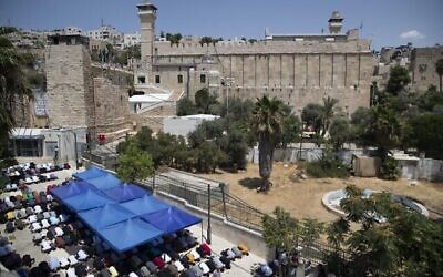 Des Palestiniens prient pour la prière du vendredi au cours d'une manifestation contre la construction de structures qui permettront aux personnes en situation de handicap de se rendre sur le Tombeau des Patriarches à Hébron, en Cisjordanie, le 13 août 2021. (Crédit : AP/Majdi Mohammed)