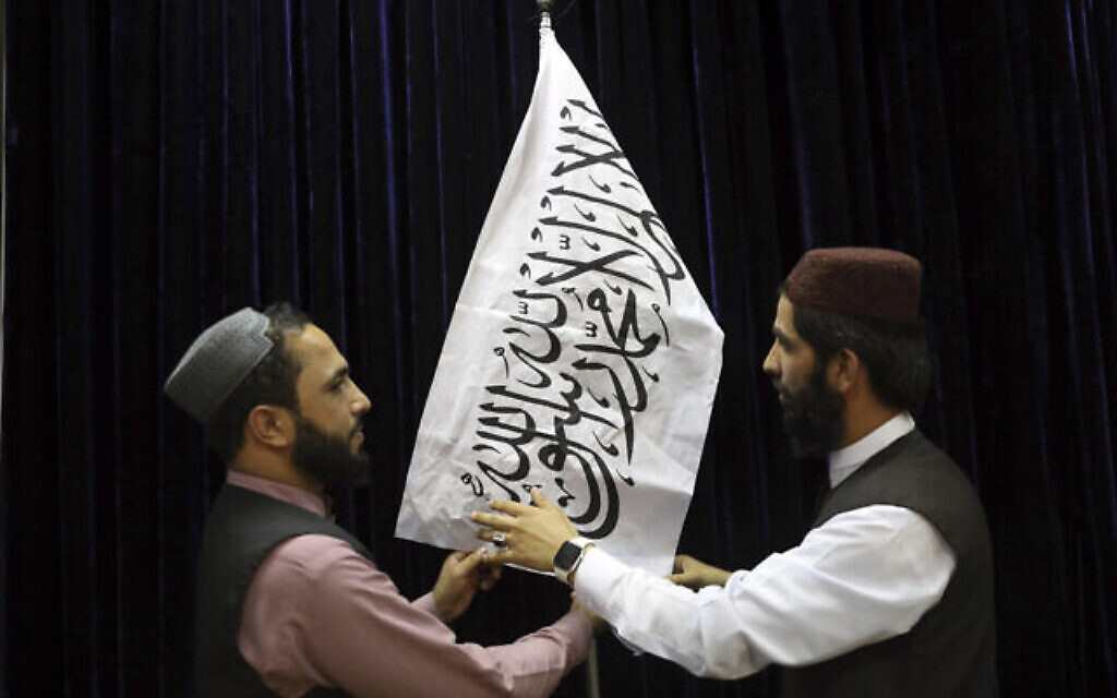 Des responsables talibans installent un drapeau taliban avant une conférence de presse du porte-parole des Talibans Zabihullah Mujahid, au Government Media Information Center à Kaboul, en Afghanistan, le 17 août 2021. (Crédit : AP Photo / Rahmat Gul)