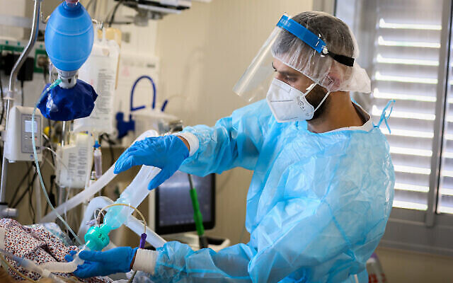 Un employé soigne un patient au service de coronavirus à l'hôpital Ziv dans la ville de Safed, dans le nord du pays, le 11 août 2021. (David Cohen / Flash90) Un employé soigne un patient au service de coronavirus à l'hôpital Ziv dans la ville de Safed, dans le nord du pays, le 11 août 2021. (David Cohen / Flash90)