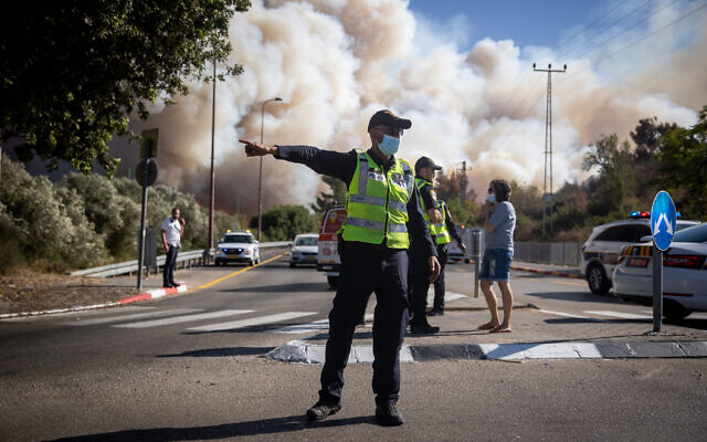 Un policier en charge de la circulation pendant l'important incendie qui a eu lieu aux abords de Jérusalem, le 15 août 2021. (Crédit : Yonatan Sindel/Flash90) Un policier en charge de la circulation pendant l'important incendie qui a eu lieu aux abords de Jérusalem, le 15 août 2021. (Crédit : Yonatan Sindel/Flash90)