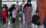Des familles évacuées de Kaboul, en Afghanistan, traversent le terminal avant de monter dans un bus après leur arrivée à l'aéroport international de Washington Dulles, à Chantilly, en Virginie, le mercredi 25 août 2021. (Crédit : AP Photo/Jose Luis Magana)