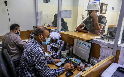 Des Palestiniens reçoivent leur aide financière dans le cadre de l'assistance accordée par le Qatar, dans un bureau de poste de Rafah, dans le sud de la bande de Gaza, le 6 octobre 2020. (Crédit : Abed Rahim Khatib/Flash90)