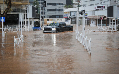 Une voiture roule sur une route inondée dans la ville de Nahariya, au nord d'Israël, le 8 janvier 2020, après qu'une rivière soit sortie de son lit. Environ 40 %, soit 250 millimètres (9,8 pouces), des précipitations annuelles moyennes de la ville sont tombées du 3 au 9 janvier de cetteannée-là. (Crédit : Meir Vaknin/Flash90)