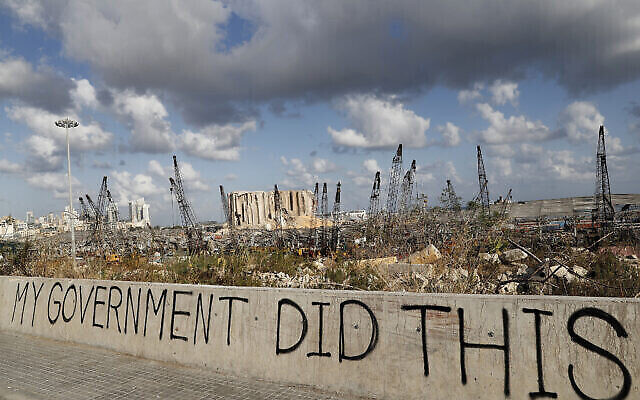 Des graffitis politiques sont visibles devant le lieu de l'explosion du 4 août qui a touché le port maritime de Beyrouth, au Liban, le 9 août 2020.(Crédit : AP/Hussein Malla)