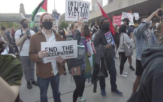 Une femme tient une pancarte sur laquelle on peut lire "Intifada jusqu'à la victoire" lors d'un rassemblement pro-palestinien organisé pendant l'opération israélienne "Gardiens des murs", au square Nathan Phillips, dans le centre-ville de Toronto, le 15 mai 2021. (Crédit : capture d'écran YouTube)
