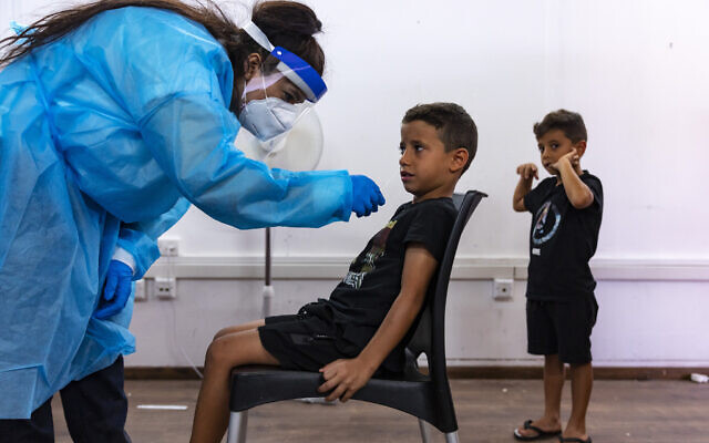 Un membre du personnel médical du Magen David Adom a prélevé un échantillon sur un enfant dans un complexe de tests COVID-19 à Jérusalem, le 18 août 2021. (Crédit : Olivier Fitoussi/Flash90) Un membre du personnel médical du Magen David Adom a prélevé un échantillon sur un enfant dans un complexe de tests COVID-19 à Jérusalem, le 18 août 2021. (Crédit : Olivier Fitoussi/Flash90)