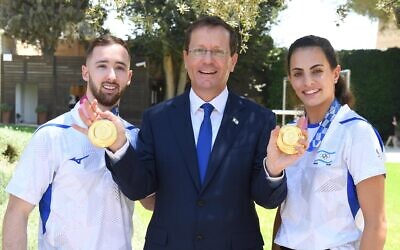 Artem Dolgopyat (G), le président Isaac Herzog (C) et Linoy Ashram (D) avec leurs médailles d'or olympiques à la résidence du président à Jérusalem, le 16 août 2021 (Crédit : Itay Beit-On/GPO).