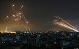 On aperçoit dans le ciel nocturne des roquettes provenant de Gaza, à droite, tirées en direction d'Israël depuis Beit Lahia, dans le nord de la bande de Gaza, le 14 mai 2021, tandis que des missiles d'interception Dome de Fer, à gauche, se dressent à leur rencontre. (Crédit : Anas Baba/AFP)