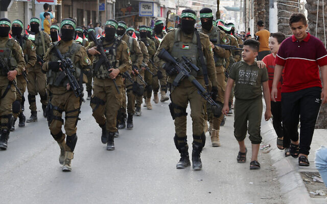 Des enfants discutent avec des membres masqués de l'aile militaire du Hamas, lors d'une marche dans les rues du camp de réfugiés de Nusseirat, dans le centre de la bande de Gaza, le 28 mai 2021. (Crédit : AP Photo/Adel Hana) Des enfants discutent avec des membres masqués de l'aile militaire du Hamas, lors d'une marche dans les rues du camp de réfugiés de Nusseirat, dans le centre de la bande de Gaza, le 28 mai 2021. (Crédit : AP Photo/Adel Hana)