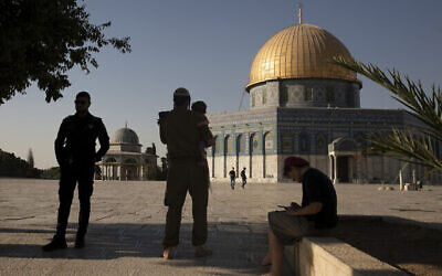 Un officier de la police israélienne (à gauche) monte la garde alors que des Juifs religieux visitent le Mont du Temple dans la Vieille Ville de Jérusalem, le 3 août 2021. (Crédit : AP Photo/Maya Alleruzzo)