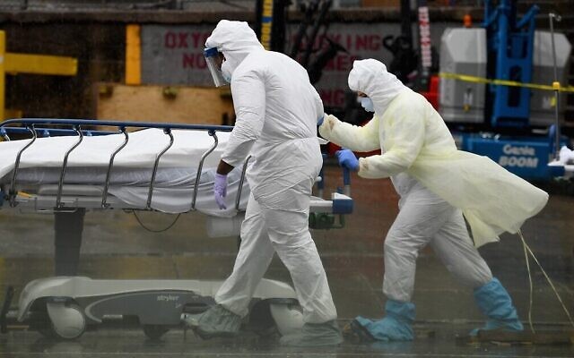 Photo d'illustration : Des personnels soignants transportent un défunt dans un camion réfrigéré servant de morgue au l Brooklyn Hospital Center à New York City, le 9 avril 2020. (Crédit : Angela Weiss/AFP)