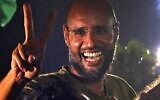 Seif al-Islam, le fils de feu le dictateur Mouammar Kadhafi,  fait le signe de la victoire devant ses soutiens et les journalistes à la résidence de son père, dans la capitale libyenne de Tripoli, le 23 août 2021. (Crédit : by IMED LAMLOUM / AFP) / ALTERNATIVE CROP