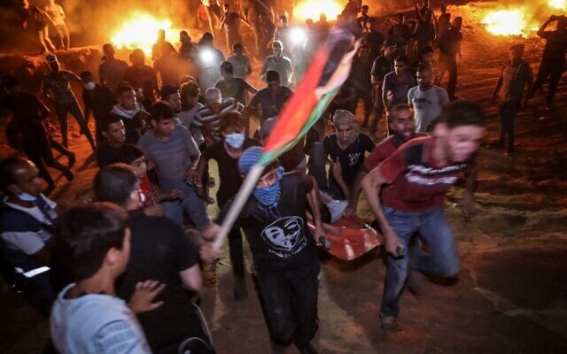 Des Palestiniens transportent un blessé pendant une manifestation nocturne à la frontière avec Israël, à l'Est de Khan Younès, dans le sud de la bande de Gaza, le 2 septembre 2021. (Crédit : SAID KHATIB / AFP)