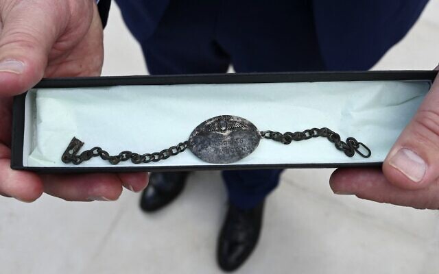Paul Habgood, le neveu du sergent Frederick Harold Habgood, pilote de la Royal Air Force britannique pendant la Seconde Guerre mondiale dont l'avion a été abattu en 1943 au-dessus de l'Alsace, tient le bracelet-chaîne de son ancêtre, retrouvé en 2018 lors de travaux d'entretien effectués au camp de concentration du Struthof, lors d'une cérémonie de remise du bracelet le 12 septembre 2021, à Natzwiller, dans l'est de la France. (Crédit : FREDERICK FLORIN / AFP)