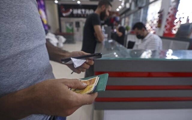 Un Palestinien recevant une aide financière versée par le Qatar dans un supermarché de Gaza City, le 15 septembre 2021. (Crédit : Mahmud Hams/AFP) Un Palestinien recevant une aide financière versée par le Qatar dans un supermarché de Gaza City, le 15 septembre 2021. (Crédit : Mahmud Hams/AFP)