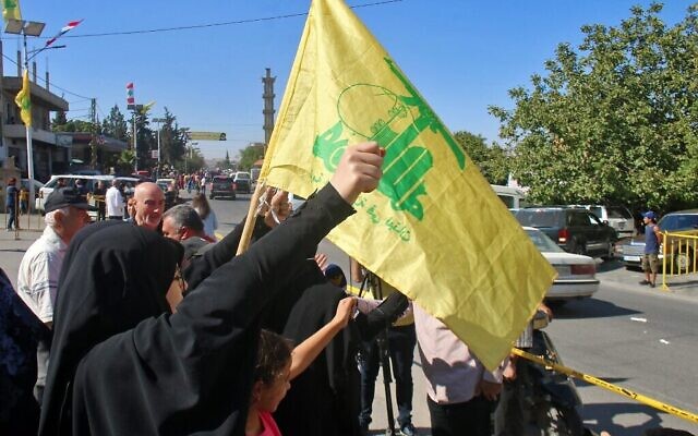 Des Libanais brandissent un drapeau du Hezbollah alors que des pétroliers transportant du carburant iranien arrivent de Syrie à al-Ain, dans la vallée de la Bekaa, à l'est du Liban, le 16 septembre 2021. (Crédit : AFP)