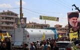 Des gens brandissent des portraits du chef du Hezbollah, Hassan Nasrallah, alors qu'ils se rassemblent pour accueillir des pétroliers transportant du carburant iranien, à leur arrivée de Syrie dans la ville de Baalbeck, dans la vallée de la Bekaa au Liban, le 16 septembre 2021. (Crédit : AFP)