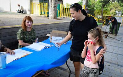 Un parent récupère un kit de test rapide COVID avant l'ouverture de la nouvelle année scolaire, à Tel Aviv, le 30 août 2021. (Crédit : Avshalom Sassoni/Flash90)