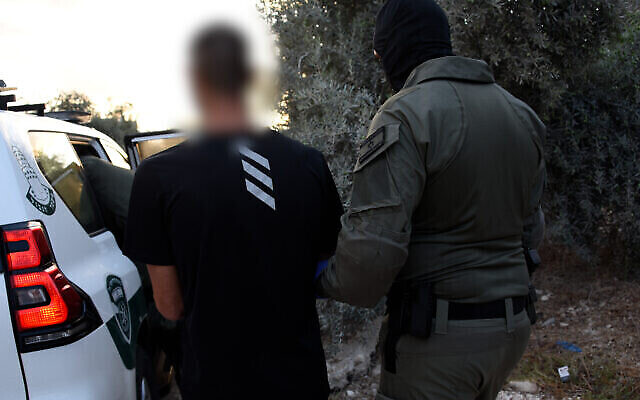 Sur cette photo du 24 septembre 2021, un policier marche avec un suspect qui a été arrêté lors d'une série de raids contre des éléments du crime organisé dans des villes arabes et druzes du nord d'Israël. (Police israélienne) Sur cette photo du 24 septembre 2021, un policier marche avec un suspect qui a été arrêté lors d'une série de raids contre des éléments du crime organisé dans des villes arabes et druzes du nord d'Israël. (Police israélienne)