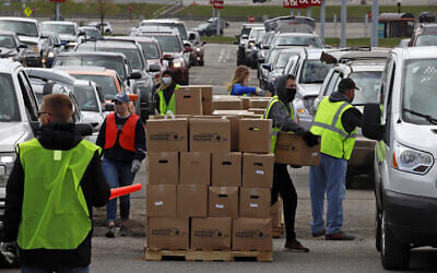 Dans une partie du parking de l'aéroport international de Pittsburgh laissée vacante par la pandémie de COVID-19, des bénévoles de la Greater Pittsburgh Community Food Bank chargent des boîtes de nourriture dans des voitures lors d'une distribution alimentaire en voiture, le 22 avril 2020. (Crédit : AP Photo/Gene J. Puskar)