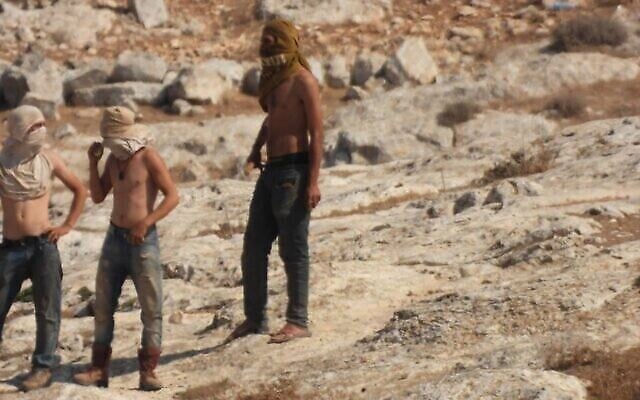 Des résidents d'implantation masqués près du hameau palestinien d'al-Mufaqara dans les collines du sud d'Hébron, le mardi 28 septembre 2021. (Crédit : autorisation) Des résidents d'implantation masqués près du hameau palestinien d'al-Mufaqara dans les collines du sud d'Hébron, le mardi 28 septembre 2021. (Crédit : autorisation)