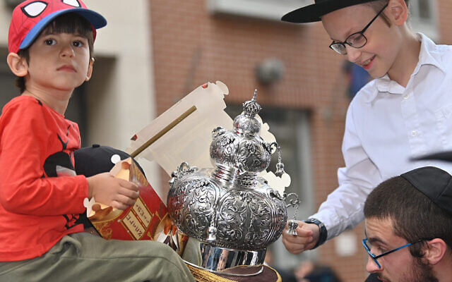 Des enfants examinent un rouleau de la Torah alors qu'il est transporté dans la synagogue de la rue Vorosmarty à Budapest, en Hongrie, le 27 août 2021. (Crédit : Cnaan Liphshiz via JTA) Des enfants examinent un rouleau de la Torah alors qu'il est transporté dans la synagogue de la rue Vorosmarty à Budapest, en Hongrie, le 27 août 2021. (Crédit : Cnaan Liphshiz via JTA)