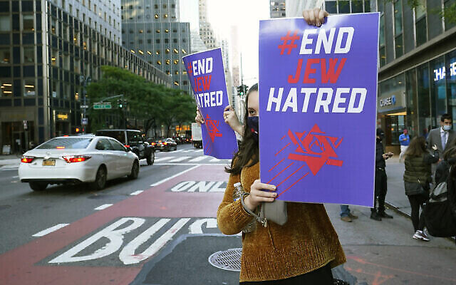 Une jeune femme tient une pancarte en direction de la circulation sur la 3e Avenue devant les bureaux du gouverneur de New York, Andrew Cuomo, jeudi 15 octobre 2020, à New York. (AP Photo/Kathy Willens)