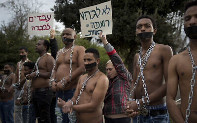 Image principale par AP/Oded Balilty : Sur cette photo du 17 janvier 2018, des migrants érythréens portent des chaînes pour imiter des esclaves lors d'une manifestation contre le projet du gouvernement israélien d'expulser de force des réfugiés et demandeurs d'asile africains d'Israël vers l'Ouganda et le Rwanda, devant la Knesset à Jérusalem.