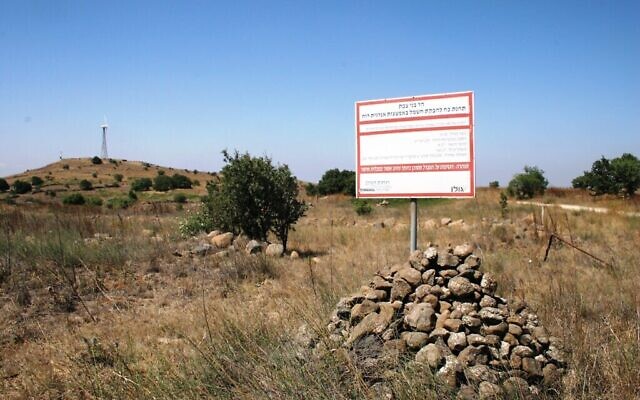 Un panneau expliquant la contribution énergétique apportée par le mémorial sous forme d'éolienne dédié à la mémoire de Simha Zeira, qui apparaît en arrière-plan. (Crédit :  Shmuel Bar-Am)