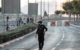 Illustration : Un policier israélien marche près de cubes de ciment placés comme barrage routier par les forces de sécurité israéliennes sur une route reliant le quartier arabe de Beit Hanina à Jérusalem-Est à Jérusalem-Ouest, le 15 septembre 2021. (Crédit : Ahmad GHARABLI / AFP)