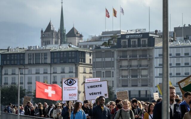 Des manifestants se rassemblent et tiennent des banderoles lors d'un rassemblement contre les mesures contre le coronavirus, le pass sanitaire Covid-19 et la vaccination à Genève, le 9 octobre 2021. (Crédit : Fabrice COFFRINI / AFP)