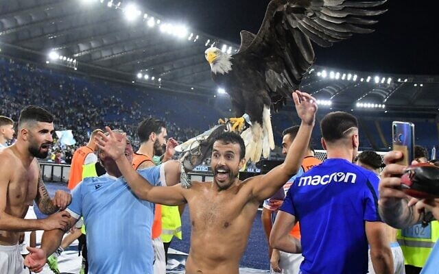 Illustration : Pedro Rodriguez Ledesma, attaquant espagnol de la Lazio, avec la mascotte de la Lazio, l'aigle Olimpia, après le match de la Lazio contre l’AS Roma au stade olympique de Rome, le 26 septembre 2021. (Crédit : Vincenzo PINTO / AFP)