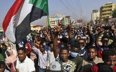 Des manifestants soudanais brandissent des drapeaux alors qu'ils se rassemblent sur la 60e rue à Khartoum, pour dénoncer les détentions nocturnes par l'armée de membres du gouvernement, le 25 octobre 2021. (Crédit : AFP)