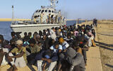 Dans cette photo d'archive du mardi 1er octobre 2019, des migrants secourus sont assis à côté d'un bateau des garde-côtes dans la ville de Khoms, en Libye, à environ 120 kilomètres à l'est de Tripoli. Les enquêteurs mandatés par l'organe suprême des droits de l'homme des Nations Unies pour examiner d'éventuels abus ont déclaré le 4 octobre 2021 avoir trouvé des preuves d'éventuels crimes de guerre et crimes contre l'humanité en Libye, en particulier contre des migrants cherchant à utiliser le pays agité d'Afrique du Nord comme moyen de se rendre en Libye. (Crédit : AP Photo/Hazem Ahmed, dossier)