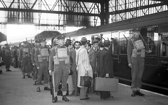 Des étrangers ennemis, qui ont été arrêtés lors d'une grande rafle policière, quittent Londres, en Angleterre, le 17 mai 1940, sous une lourde escorte militaire en direction des camps d'internement. (Crédit : photo AP)