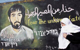 Une Palestinienne passe devant une peinture murale réalisée par un artiste du Hamas représentant le soldat israélien capturé Ron Arad, dans le camp de réfugiés de Jabalia, dans la bande de Gaza, le 28 janvier 2010. (Crédit : Abed Rahim Khatib/Flash90)